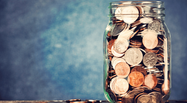 Clear jar full of coins with a blue/white background and coins laying around the jar. Church Equip Curriculum Money In the Light of Eternity