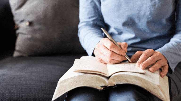person sitting on chair with open bible and notebook on lap, writing in notebook Church Equip A Journey Through the New Testament Church Equip Curriculum